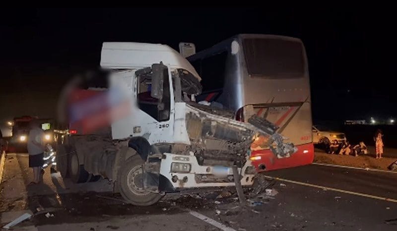 Caminhão bate em dois ônibus e motorista fica preso às ferragens